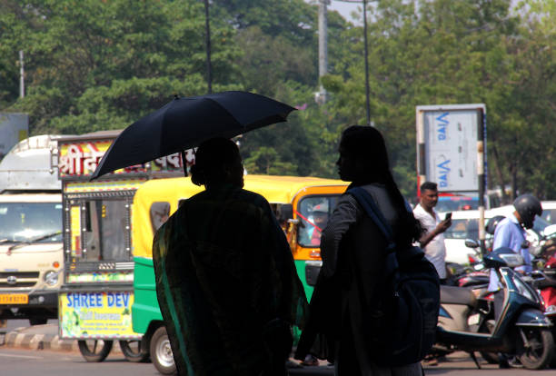 Pedestrians are seen at the daily market area in Bhubaneswar, Odisha, India, on this hot afternoon, shielding themselves with clothes and umbrellas to temperature